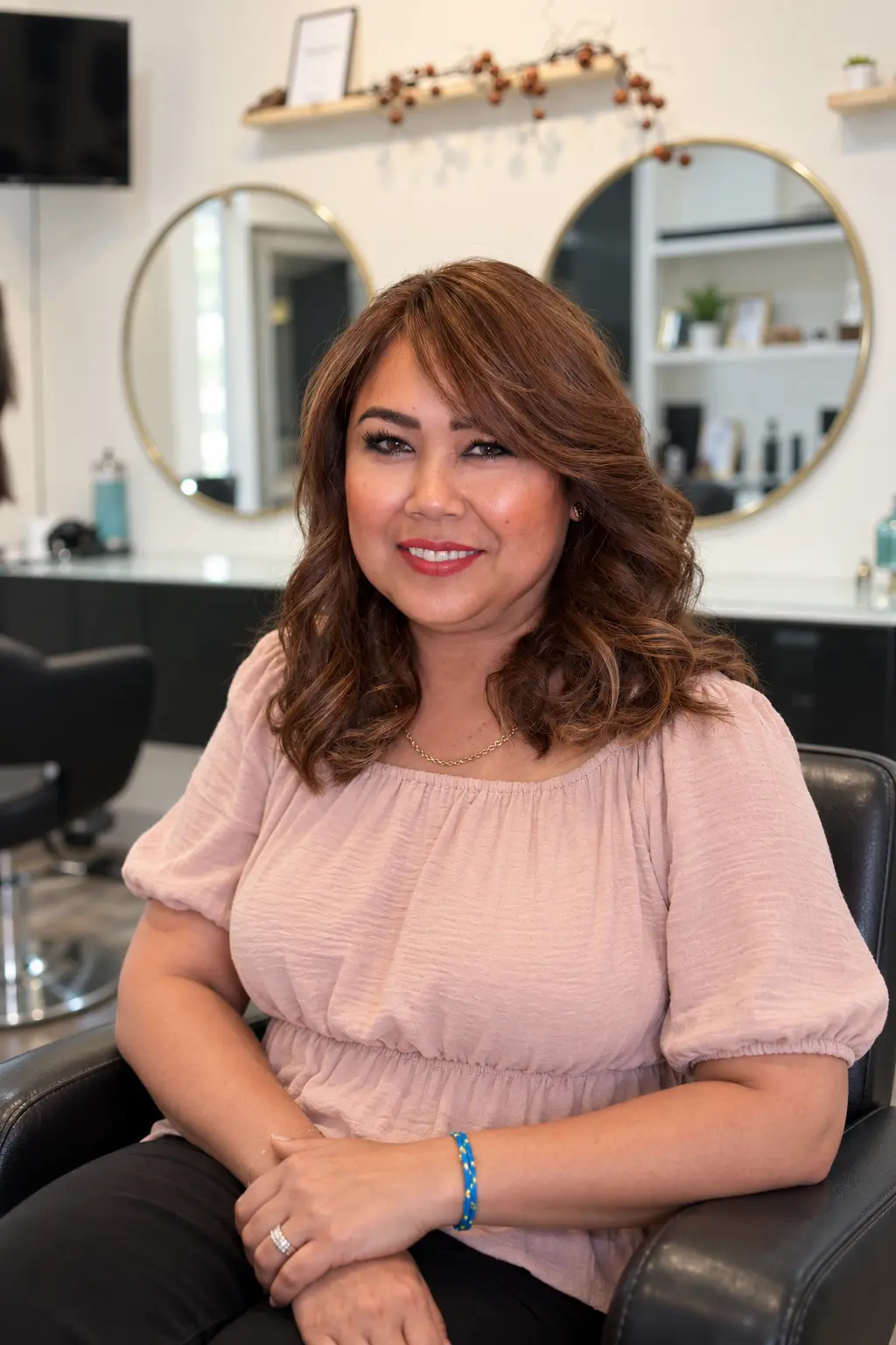 Client with soft warm brunette waves seated in Nasrin Salon